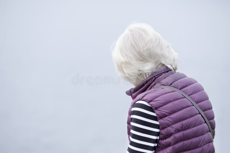 Pensée pluse âgé supérieure de dame triste et isolée contre le ciel clair vide de fond photographie stock Pensée pluse âgé supérieure de dame triste et isolée contre le ciel clair vide de fond photographie stock