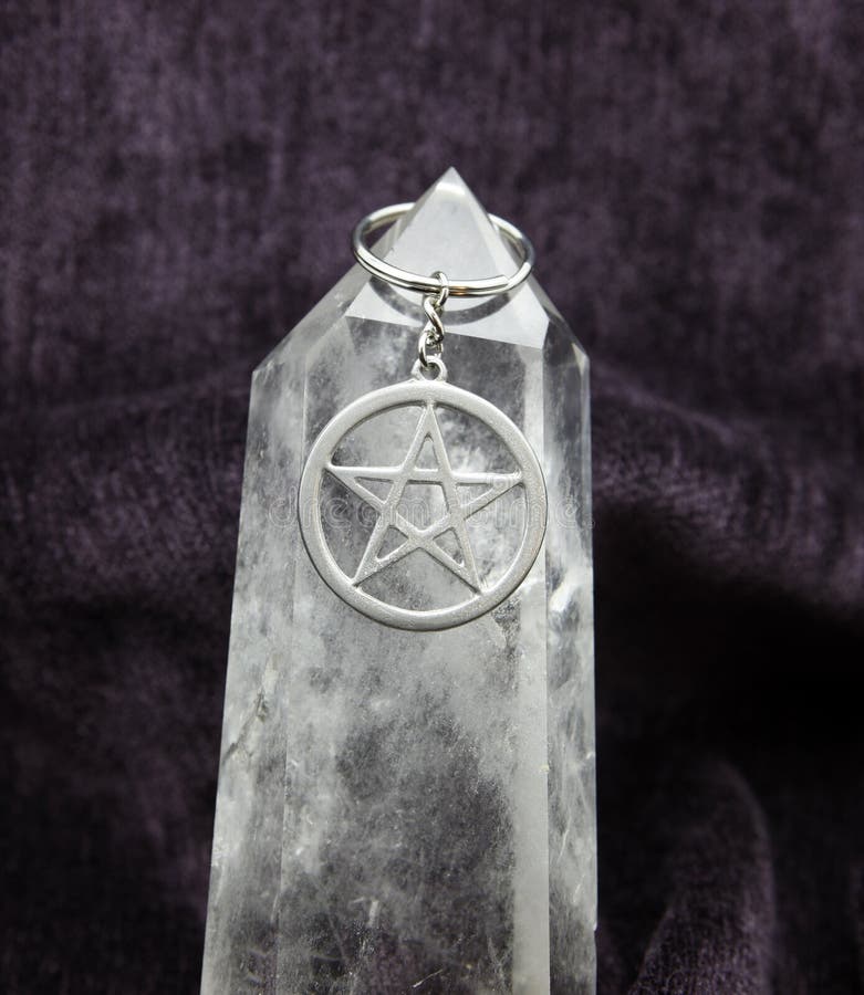 Strieborné pentacle na reťazi, visí obrovský kremeň prútik, s fialová velvet pozadí.