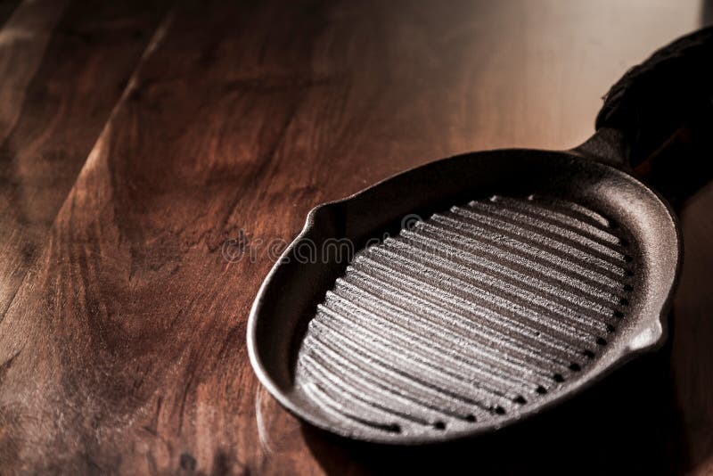 Empty clean cast iron griddle pan on a rustic wooden table with copy space, high angle view. Empty clean cast iron griddle pan on a rustic wooden table with copy space, high angle view