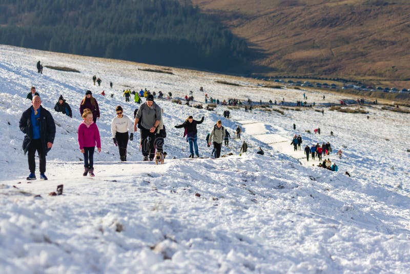 PEN-Y-FAN, WALES, UK - DECEMBER 06 2020: Large numbers of walkers and hikers enjoying fresh snow on Pen-y-Fan mountain in the Brecon Beacons National Park. This was the first snowfall of the winter season. PEN-Y-FAN, WALES, UK - DECEMBER 06 2020: Large numbers of walkers and hikers enjoying fresh snow on Pen-y-Fan mountain in the Brecon Beacons National Park. This was the first snowfall of the winter season