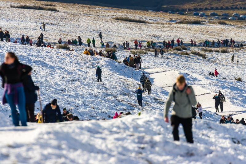 PEN-Y-FAN, WALES, UK - DECEMBER 06 2020: Large numbers of walkers and hikers enjoying fresh snow on Pen-y-Fan mountain in the Brecon Beacons National Park. This was the first snowfall of the winter season. PEN-Y-FAN, WALES, UK - DECEMBER 06 2020: Large numbers of walkers and hikers enjoying fresh snow on Pen-y-Fan mountain in the Brecon Beacons National Park. This was the first snowfall of the winter season