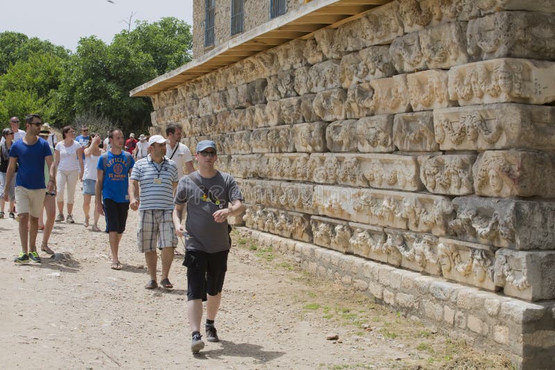 Peolpe walk in front of Friezes on the Portico of Tiberius in Ap