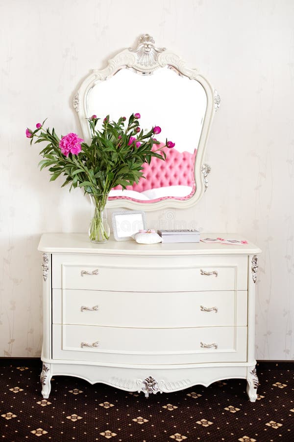 Peony flowers on a white commode under a mirror. Wedding morning