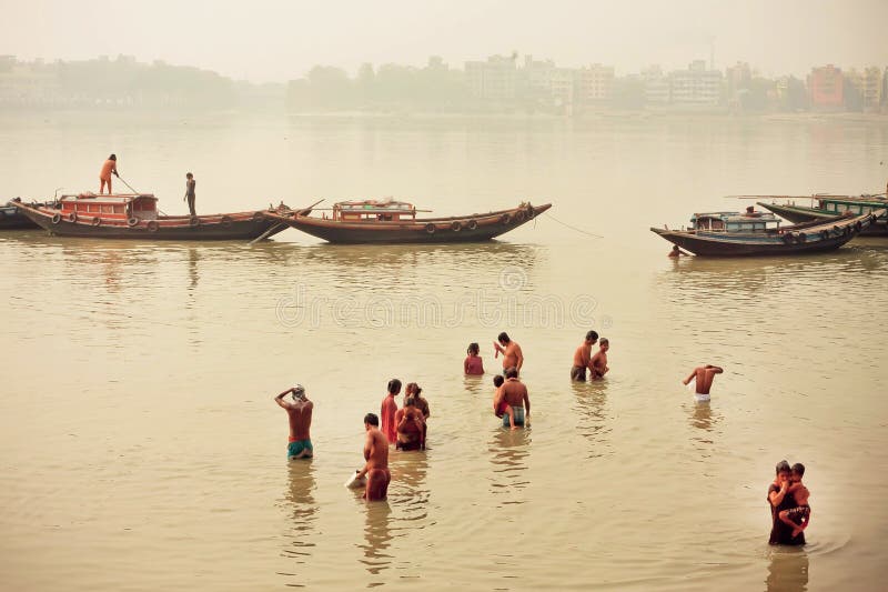 People bathing in dirty water of indian river past the riverboats