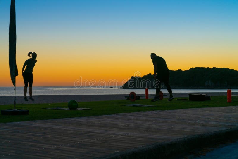 People on beach at Mount Maunganui at sunrise in silhouette doing morning fitnes exercise and walking by stock photography People on beach at Mount Maunganui at sunrise in silhouette doing morning fitnes exercise and walking by stock photography