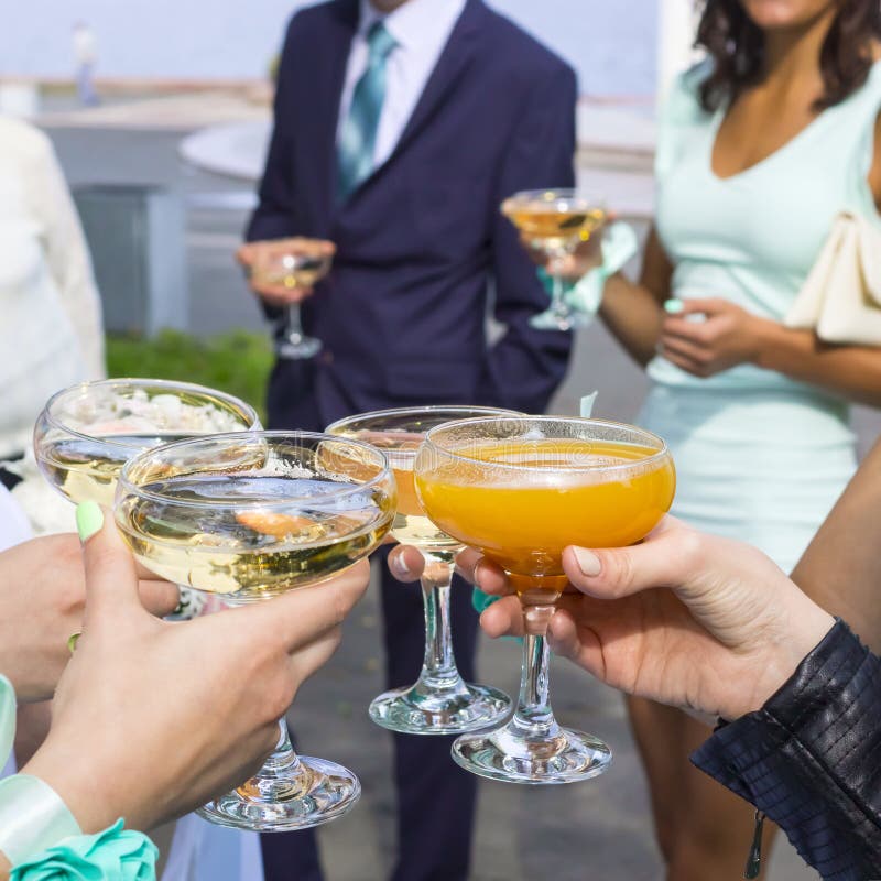 People celebrate wedding with glasses outside. People celebrate wedding with glasses outside