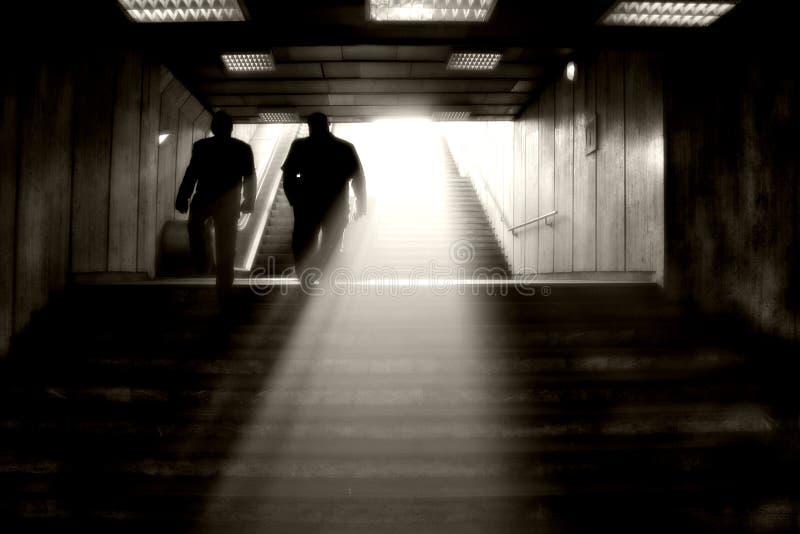 People climbing stairs in the light at the subway