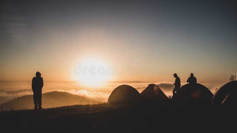 Cámping, llegada afuera de a ellos tiendas de campana sobre el mirar amanecer de montana, mientras nubes Ellos son bajo.