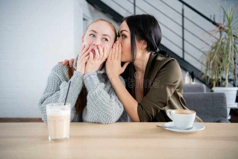 People communication and friendship concept - smiling young women drinking coffee or tea and gossiping at outdoor cafe stock image People communication and friendship concept - smiling young women drinking coffee or tea and gossiping at outdoor cafe stock image