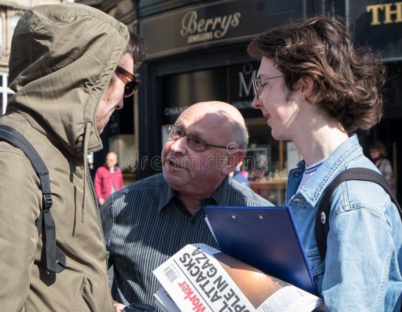 People debating politics on the street.  One person holding a copy of Socialist Worker