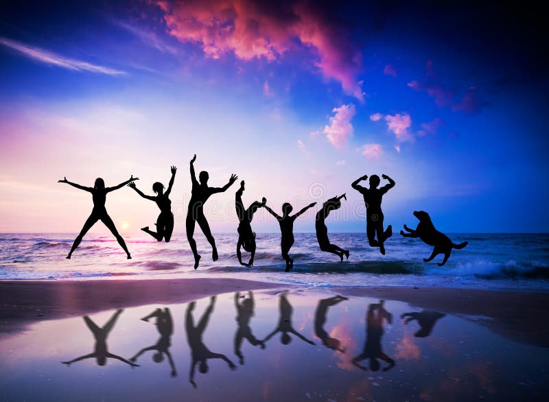 People and dog jumping on beach