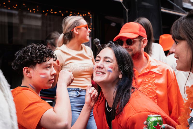 People in orange clothing are sailing in a boat on the canals of Amsterdam on King\ s Day