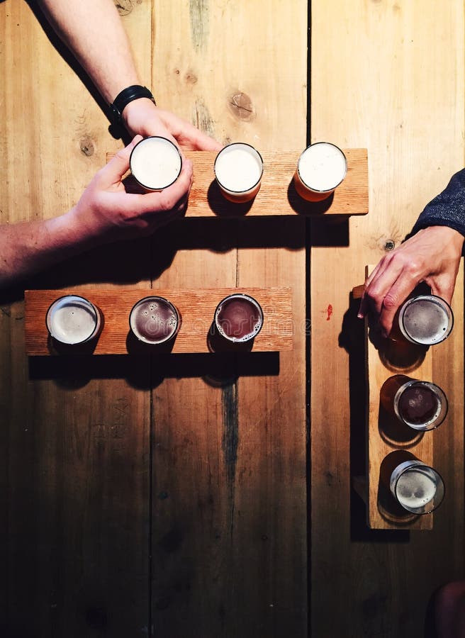 People drinking local beer from tasting palettes at craft brewery