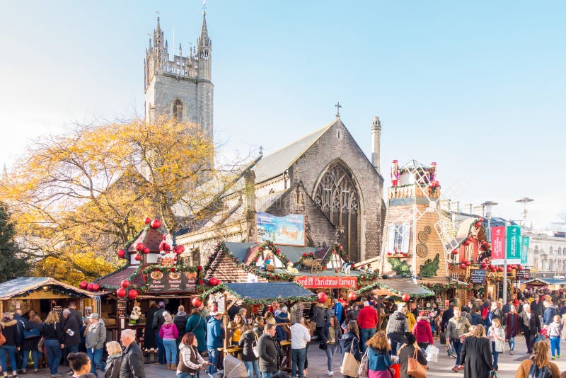 Cardiff, Wales, United Kingdom - November 19, 2017: People are eating at the food stalls while visiting the Christmas Market in Cardiff, UK in November 2017. Cardiff, Wales, United Kingdom - November 19, 2017: People are eating at the food stalls while visiting the Christmas Market in Cardiff, UK in November 2017.