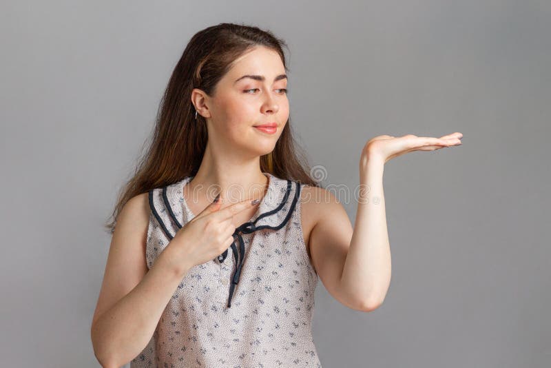 People and emotions. A young brunette in a blouse smiling and points her hand and finger to the side. Copy space royalty free stock image People and emotions. A young brunette in a blouse smiling and points her hand and finger to the side. Copy space royalty free stock image