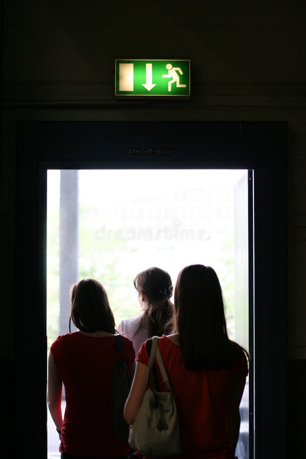 Tři dívky exit budovy, na dveře exit.