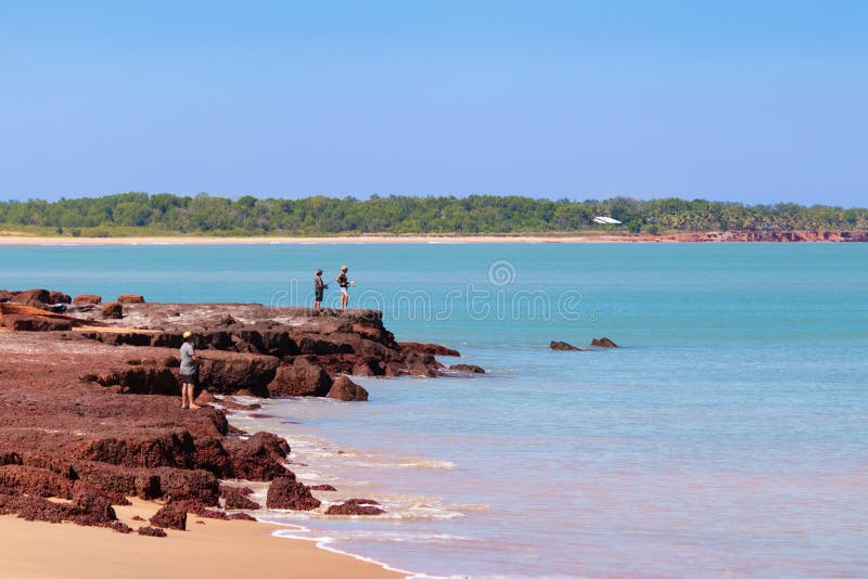 People fishing from the coast. Land based fishing, anglers catching fish barramundi. Rocky shore. Vivid colors. Dundee Beach