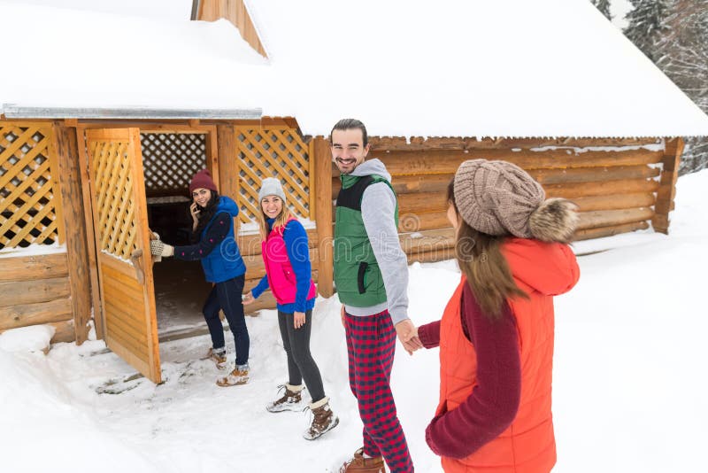 People Group Near Wooden Country House Winter Snow Resort Cottage. Leisure, lifestyle.