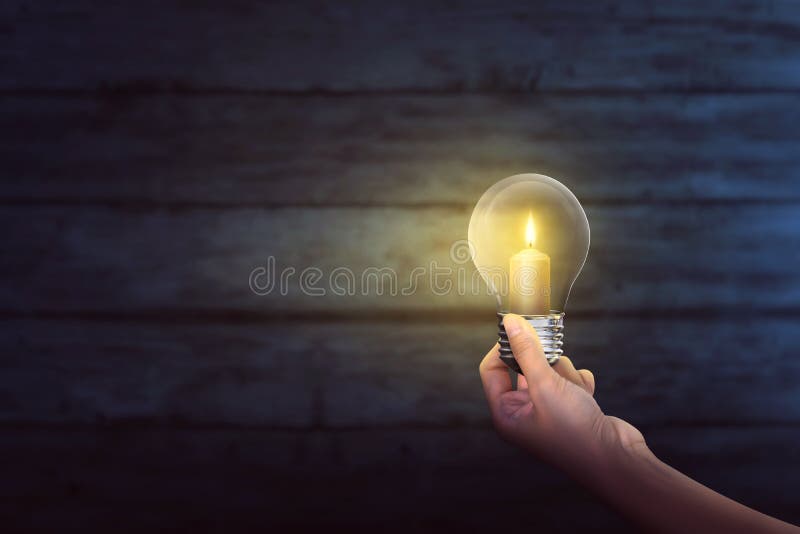 People hand holding bright candle inside light bulb royalty free stock photography