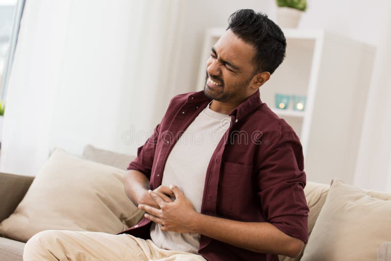 Unhappy man suffering from stomach ache at home stock image Unhappy man suffering from stomach ache at home stock image