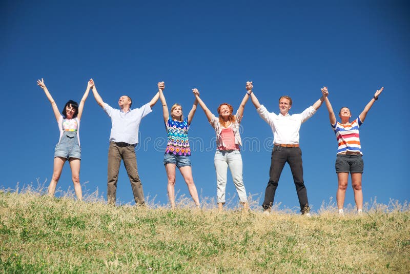 People on hill raise hands together