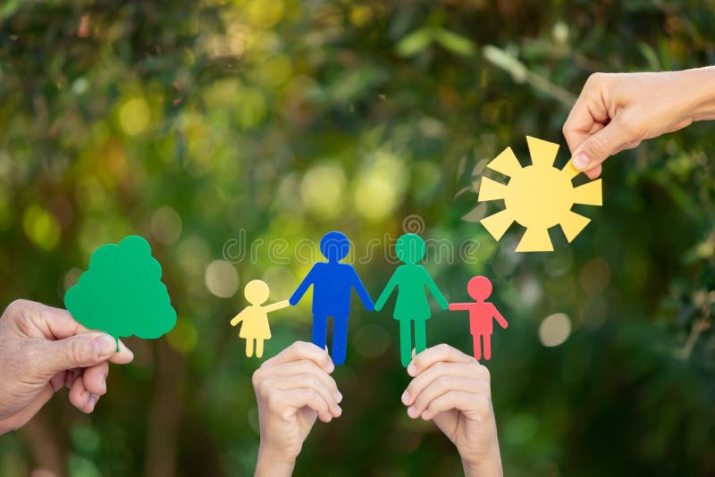 People holding paper family in hands against spring green background stock photo People holding paper family in hands against spring green background stock photo