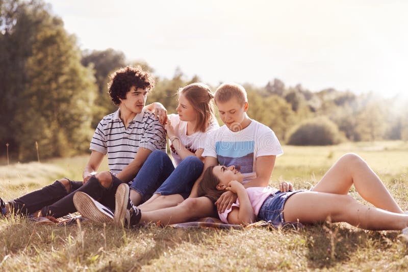 Joyful two couples dressed in summer casual clothes, spend free time in cou...