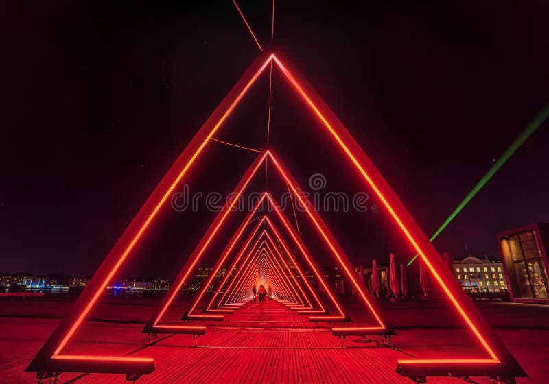 People look like across an extraterrestrial world in the middle of a series of triangular gates of light or red light tunnel royalty free stock photos