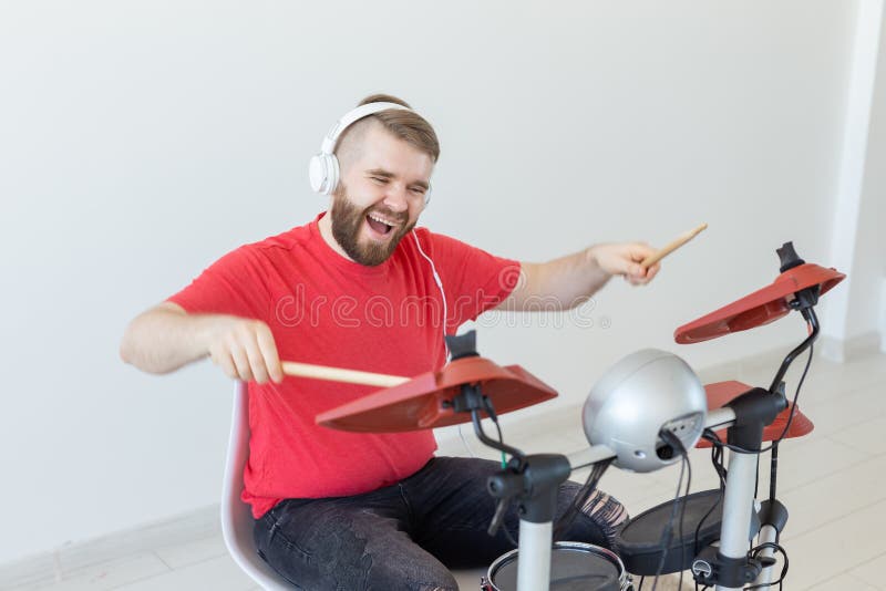 People, music and hobby concept - Man with white headphones playing the drums set over light background stock photos People, music and hobby concept - Man with white headphones playing the drums set over light background stock photos
