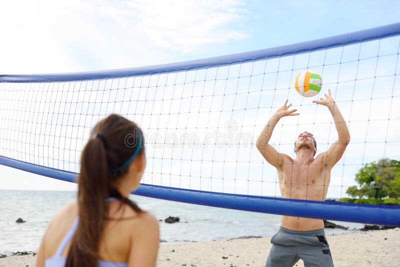 People playing beach volleyball having fun in sporty active lifestyle. Man hitting volley ball in game in summer. Woman and men fitness model living healthy lifestyle doing sport on beach. People playing beach volleyball having fun in sporty active lifestyle. Man hitting volley ball in game in summer. Woman and men fitness model living healthy lifestyle doing sport on beach.