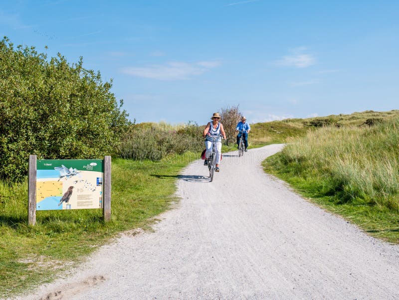 People riding bikes and information board in dunes of nature reserve Het Oerd on West Frisian island Ameland, Friesland, royalty free stock photo People riding bikes and information board in dunes of nature reserve Het Oerd on West Frisian island Ameland, Friesland, royalty free stock photo
