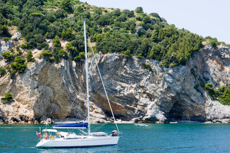 People sailing with a sailboat in front of Palmaria island