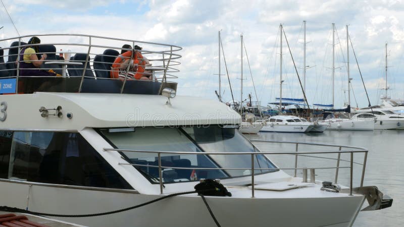 People sitting aboard a pleasure boat, which stands at the pier.