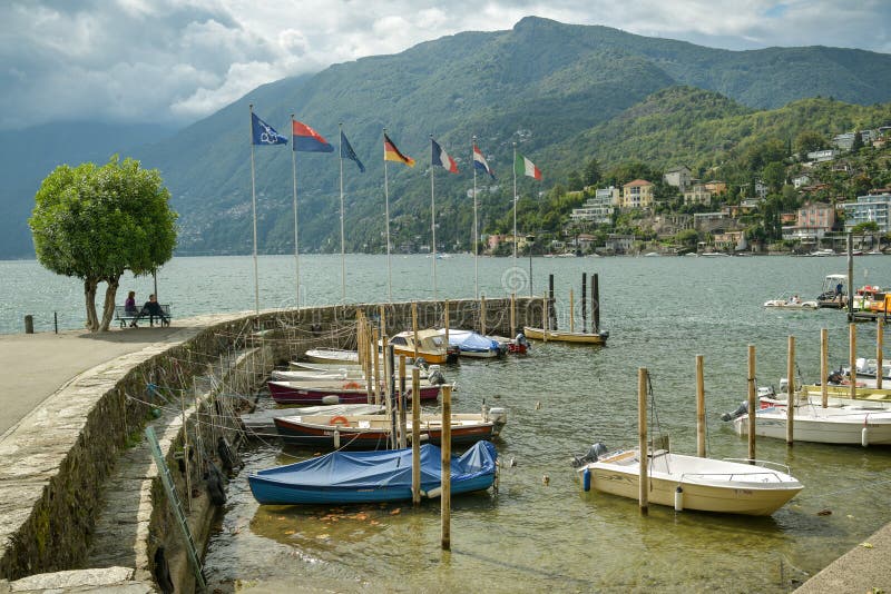 People sitting on bench near small port on Lago Maggiore in Ascona, Switzerland stock photo People sitting on bench near small port on Lago Maggiore in Ascona, Switzerland stock photo