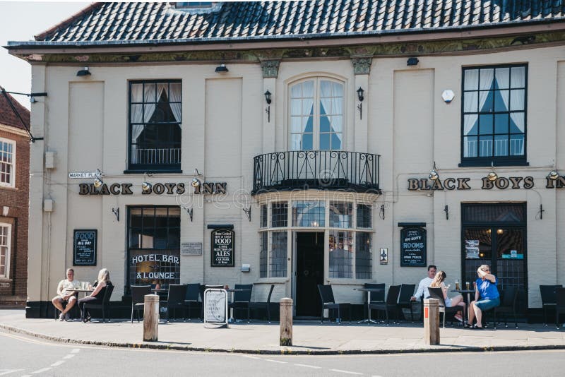 Aulsham, UK - April 21, 2019: People sitting at the outdoor tables of Black Boys Inn pub in Aylsham, a historic market town and civil parish on the River Bure in north Norfolk, England. Aulsham, UK - April 21, 2019: People sitting at the outdoor tables of Black Boys Inn pub in Aylsham, a historic market town and civil parish on the River Bure in north Norfolk, England