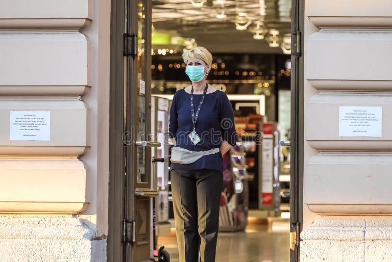 People on the street coronavirus. Zagreb, Croatia - March 19, 2020 : A shop employee stands at the entrance and disinfects the hands of shoppers entering the royalty free stock photos People on the street coronavirus. Zagreb, Croatia - March 19, 2020 : A shop employee stands at the entrance and disinfects the hands of shoppers entering the royalty free stock photos