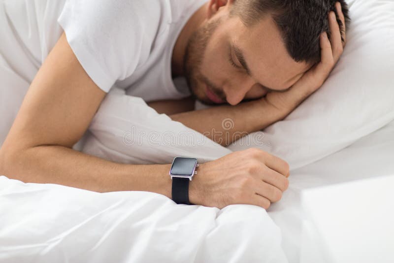 Close up of man with smart watch sleeping in bed