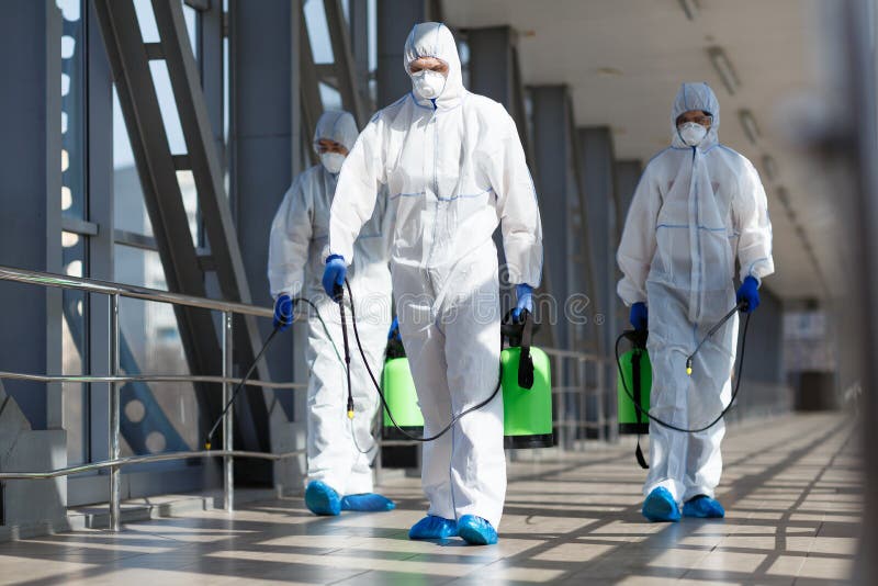 People in virus protective suits and mask disinfecting buildings royalty free stock image