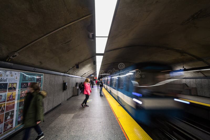 People waiting for a subway in Cote des Neiges station platform, blue line, while a metro train is coming, with a speed blur