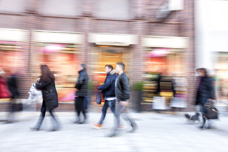 People walking against shop window, zoom effect, motion blur