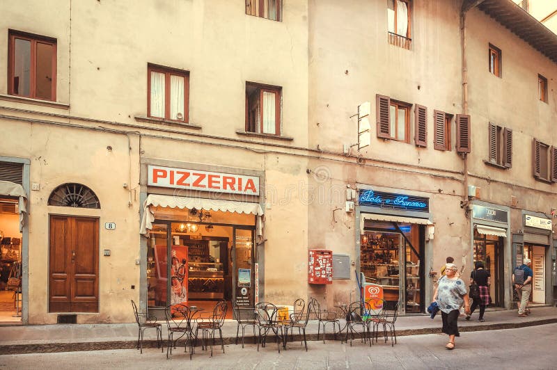 People walking around pizzeria in old house of the ancient Tuscany city stock photo People walking around pizzeria in old house of the ancient Tuscany city stock photo