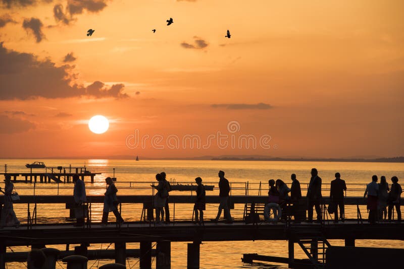 People walking on sunset over bridge on lake stock image People walking on sunset over bridge on lake stock image