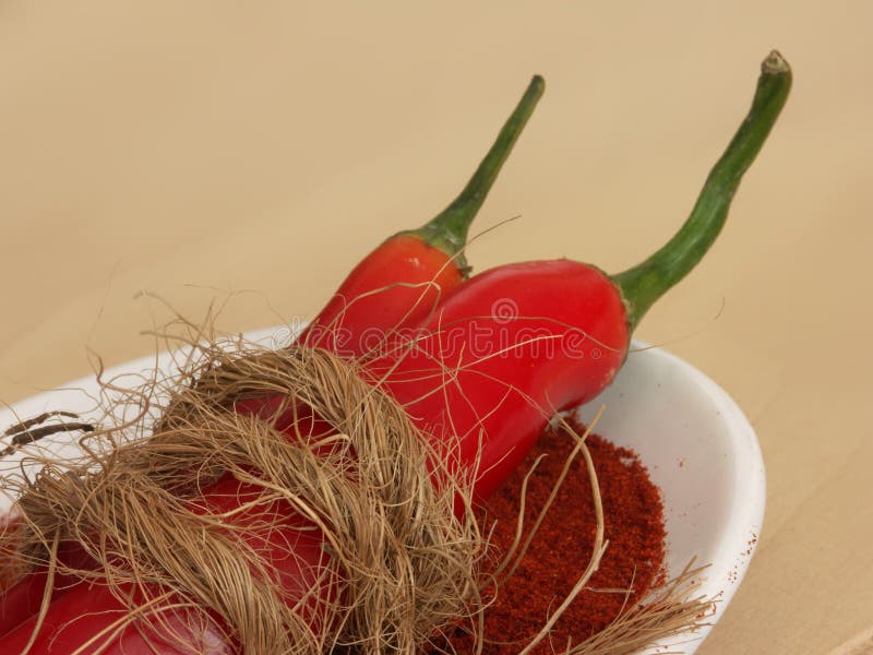 Both whole and ground red chili pepper in a dish with garnish. Both whole and ground red chili pepper in a dish with garnish.