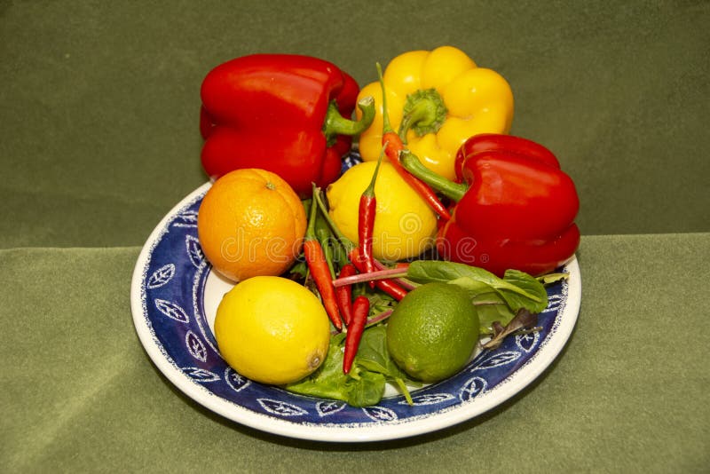Peperoni rossi e peperoni di lievito, limone, limoni, arancioni su piastra blu fotografie stock Peperoni rossi e peperoni di lievito, limone, limoni, arancioni su piastra blu fotografie stock