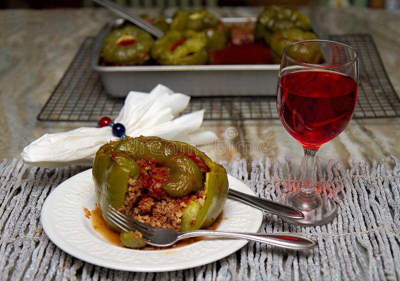 Peperoni verdi farciti in salsa al pomodoro con vetro di vino rosso Fondo bollente del piatto immagini stock libere da diritti Peperoni verdi farciti in salsa al pomodoro con vetro di vino rosso Fondo bollente del piatto immagini stock libere da diritti