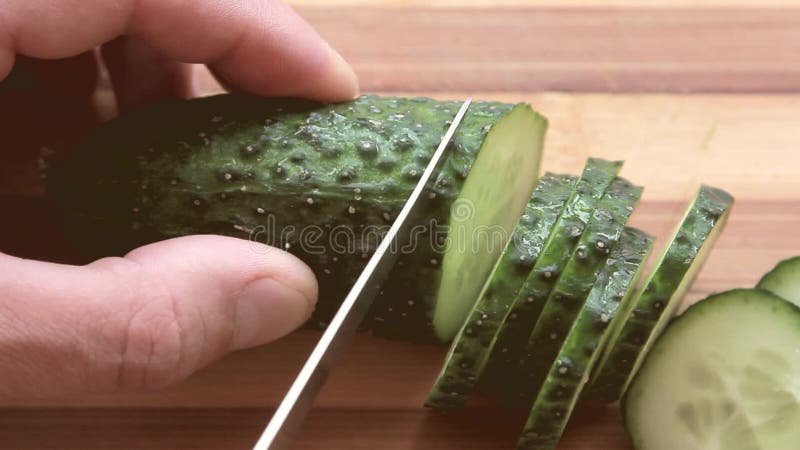 Pepino fresco cortado en un tablero de madera con un cuchillo almacen de metraje de vídeo