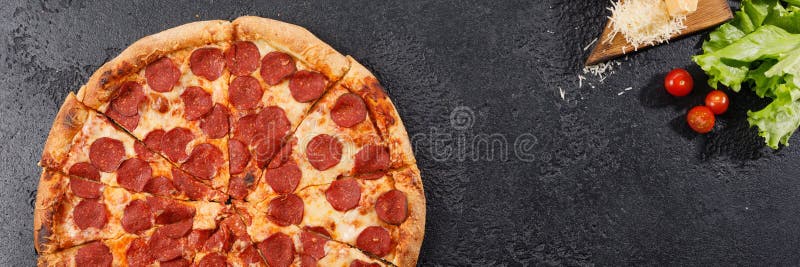 Pepperoni pizza on a black texture background. Still life. Top view stock photography