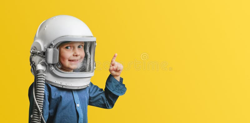 Un niño con un casco de astronauta y mirando hacia arriba.