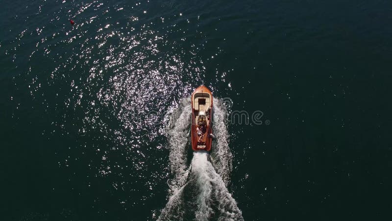 Pequeno barco a motor marrom flutua no mar deixando uma trilha de espuma