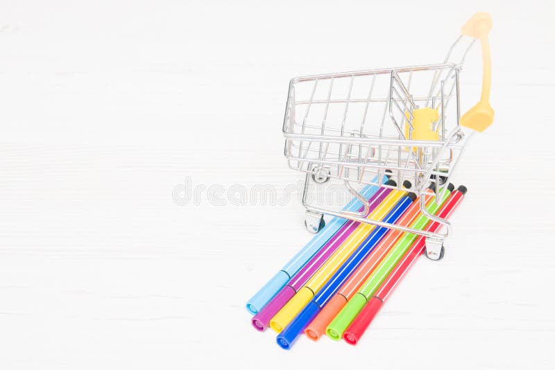Pequeno carrinho de compras e canetas de feltro de cores arco-íris imagem de stock royalty free Pequeno carrinho de compras e canetas de feltro de cores arco-íris imagem de stock royalty free